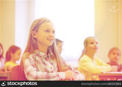 education, elementary school, learning and people concept - group of school kids with notebooks sitting in classroom