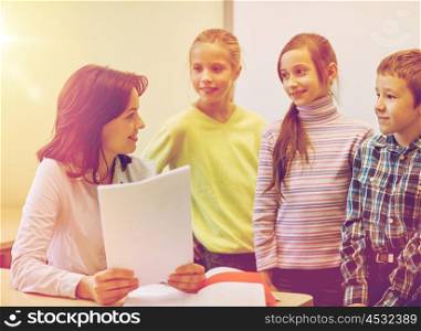 education, elementary school, learning and people concept - group of school kids with teacher talking in classroom