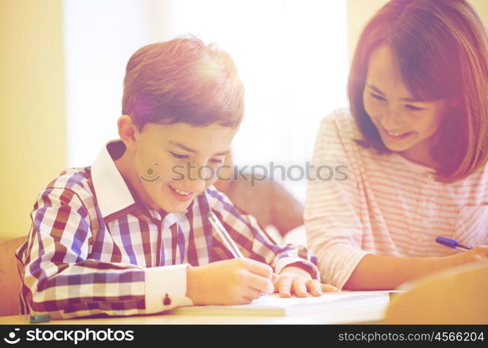 education, elementary school, learning and people concept - group of school kids with pens and notebooks writing test in classroom