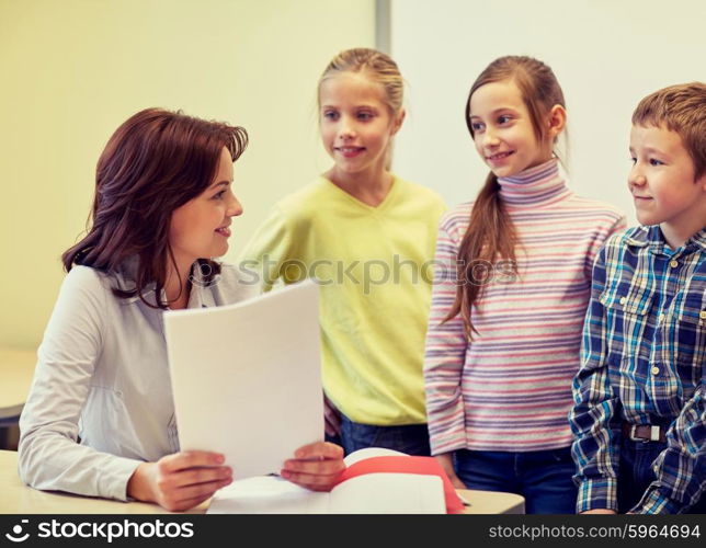education, elementary school, learning and people concept - group of school kids with teacher talking in classroom