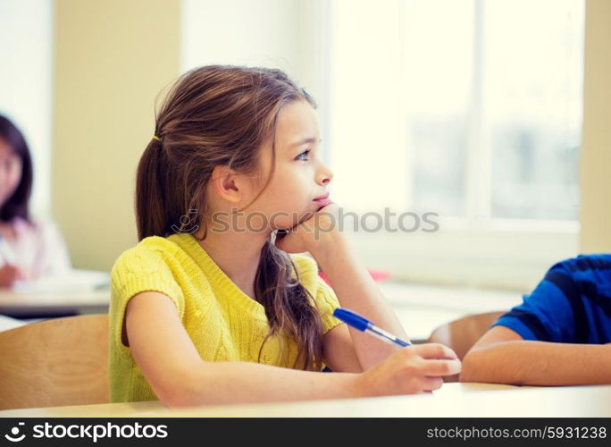 education, elementary school, learning and people concept - school girl with pen being bored in classroom