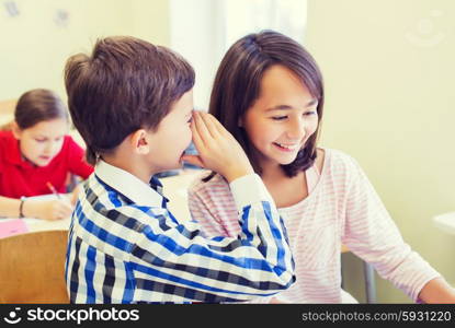 education, elementary school, learning and people concept - smiling schoolboy whispering secret to classmate ear in classroom