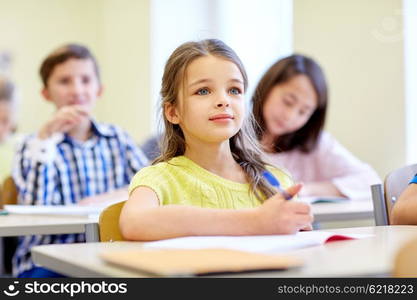 education, elementary school, learning, children and people concept - student girl with group of classmates on lesson in classroom