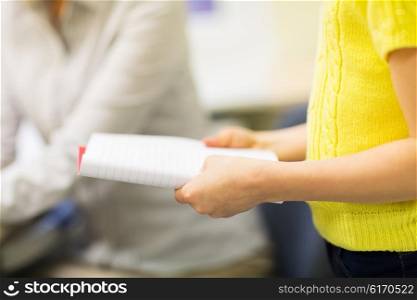 education, elementary school, learning, examination and people concept - close up of girl with notebook at school lesson