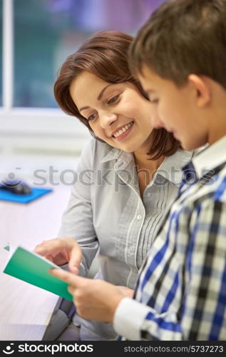 education, elementary school, learning, examination and people concept - school boy with notebook and teacher in classroom