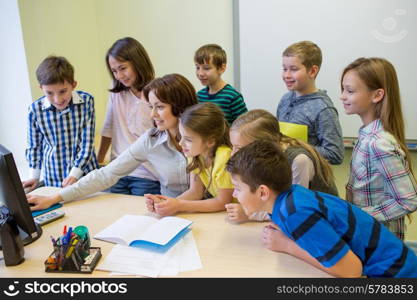 education, elementary school, learning, technology and people concept - group of school kids with teacher looking to computer monitor in classroom