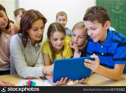 education, elementary school, learning, technology and people concept - group of school kids with teacher looking to tablet pc computer in classroom