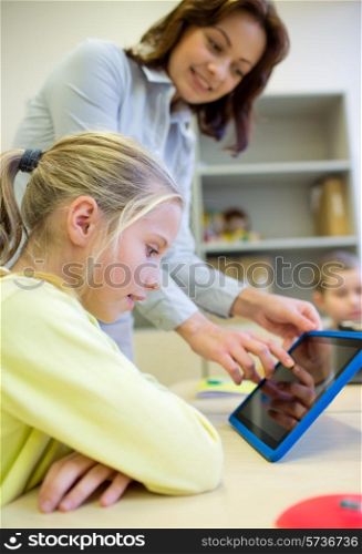 education, elementary school, learning, technology and people concept - little girl with teacher and tablet pc computer in classroom