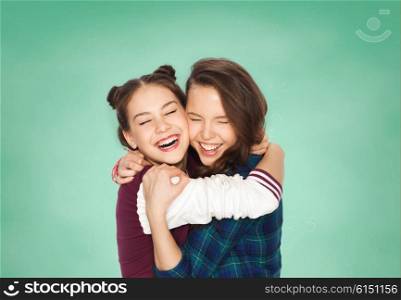 education, emotions, teens and friendship concept - happy smiling pretty teenage student girls hugging and laughing over green school chalk board background