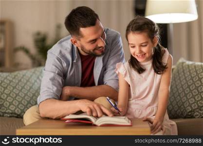 education, family and homework concept - happy father and daughter with book doing homework at home. father and daughter doing homework together