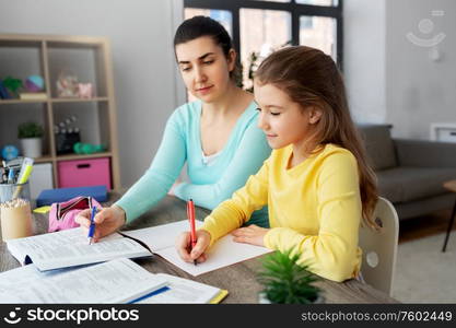 education, family and homework concept - happy mother and daughter with book writing to notebook at home. mother and daughter doing homework together