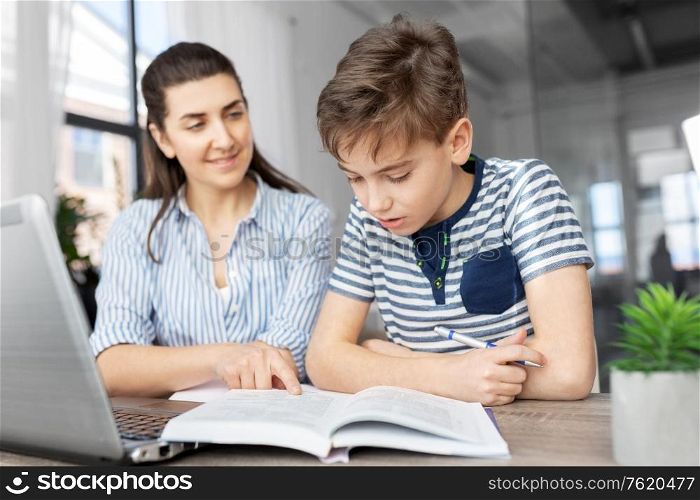education, family and homework concept - smiling mother and son with book writing to notebook at home. mother and son doing homework together