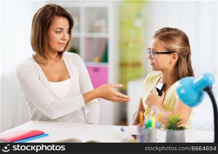education, family and learning concept - displeased mother taking smartphone from daughter doing homework at home. displeased mother taking smartphone from daughter