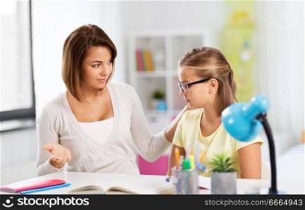 education, family and learning concept - displeased mother talking to daughter while doing homework at home. upset mother talking to daughter doing homework