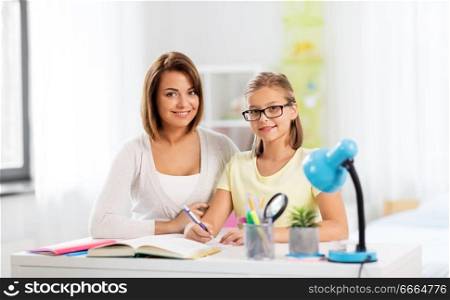 education, family and learning concept - mother and daughter doing homework together at home. mother and daughter doing homework together