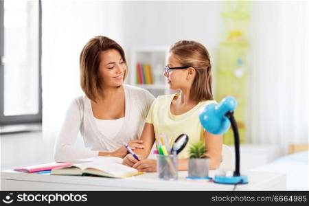 education, family and learning concept - mother and daughter doing homework together at home. mother and daughter doing homework together