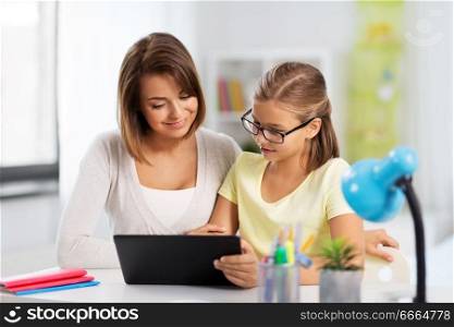 education, family and learning concept - mother and daughter with tablet pc computer doing homework together at home. mother and daughter with tablet pc doing homework