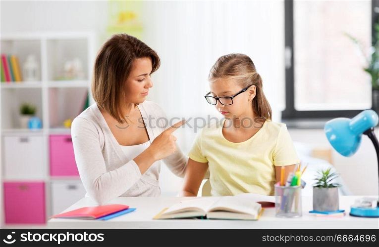 education, family and learning concept - strict mother talking to daughter while doing homework at home. strict mother talking to daughter doing homework