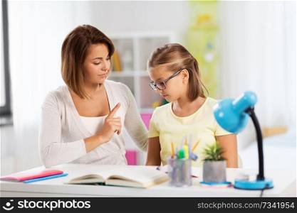 education, family and learning concept - strict mother talking to daughter while doing homework at home. strict mother talking to daughter doing homework