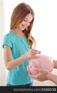 education, family, child and money saving concept - father holding piggy bank and child putting coins into it