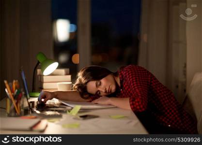 education, freelance, overwork and people concept - tired student woman sleeping on table at night home. student or woman sleeping on table at night home