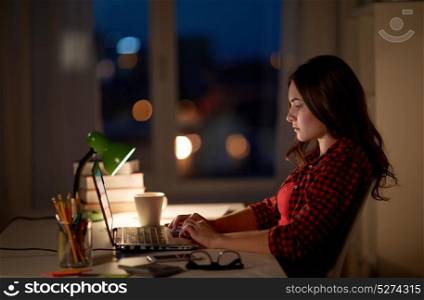 education, freelance, technology, overwork and people concept - woman or student girl typing on laptop computer at night home. student or woman typing on laptop at night home