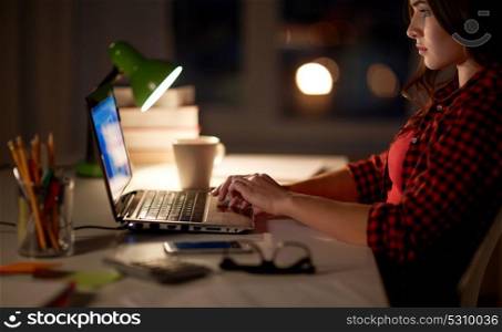 education, freelance, technology, overwork and people concept - woman or student girl typing on laptop computer at night home. student or woman typing on laptop at night home