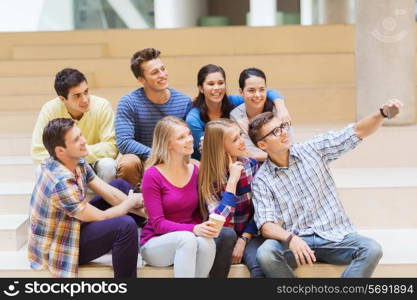 education, friendship, drinks, technology and people concept - group of smiling students with smartphone and paper coffee cup taking selfie at school