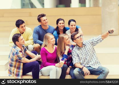 education, friendship, drinks, technology and people concept - group of smiling students with smartphone and paper coffee cup taking selfie at school