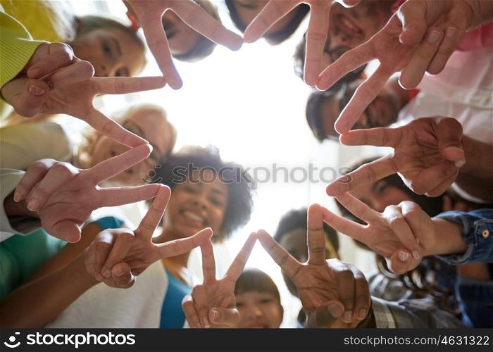 education, friendship, gesture, victory and people concept - group of happy international students or friends standing in circle and showing peace or v sign