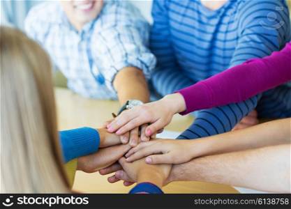 education, friendship, teamwork and people concept - close up of high school students putting hands on top of each other