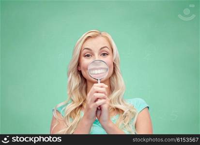 education, fun, emotions, expressions and people concept - happy smiling young woman or teenage girl having fun with magnifying glass over green school chalk board background