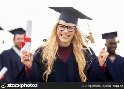 education, gesture and people concept - group of happy international students in mortar boards and bachelor gowns with diplomas celebrating successful graduation