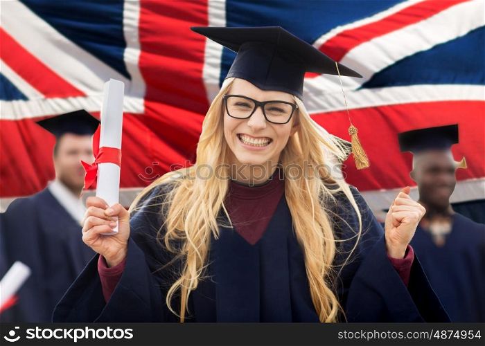 education, gesture and people concept - group of happy international students in mortarboards and bachelor gowns with diplomas celebrating successful graduation over english flag background