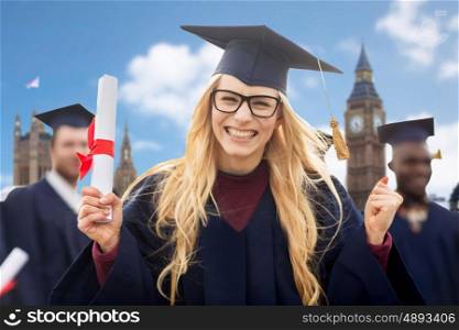 education, gesture and people concept - group of happy international students in mortarboards and bachelor gowns with diplomas celebrating successful graduation over london background