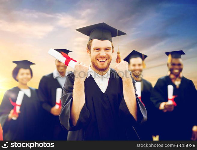 education, gesture and people concept - group of happy international students in mortar boards and bachelor gowns with diplomas celebrating successful graduation. happy student with diploma celebrating graduation