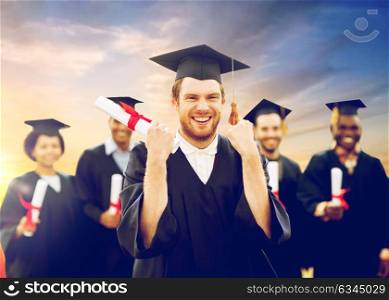 education, gesture and people concept - group of happy international students in mortar boards and bachelor gowns with diplomas celebrating successful graduation. happy student with diploma celebrating graduation