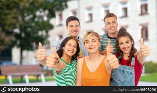 education, gesture and people concept - group of happy smiling friends showing thumbs up over school or campus background. happy friends showing thumbs up