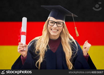 education, gesture and people concept - happy female student in mortar board and bachelor gown with diploma celebrating successful graduation over german flag background