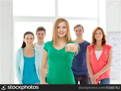 education, gesture and school concept - group of smiling students with teenage girl in front pointing at you