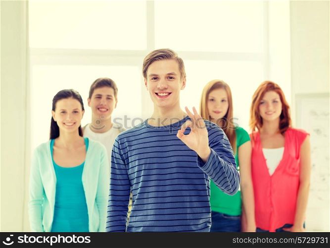education, gesture and school concept - group of smiling students with teenage boy in front showing ok sign