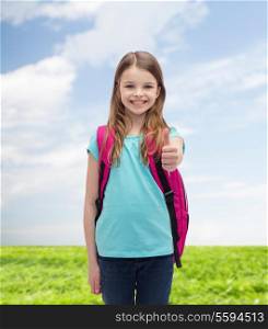 education, gesture and school concept - happy and smiling little girl with school bag showing thumbs up