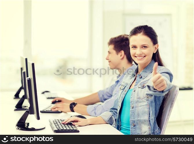 education, gesture, technology and school concept - two smiling students in computer class and girl showing thumbs up
