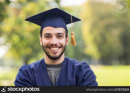 education, graduation and people concept - close up of happy student in mortar boards and bachelor gown outdoors