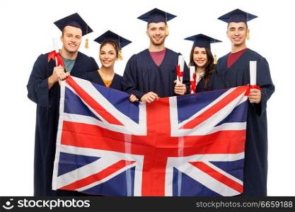 education, graduation and people concept - group of happy graduate students in mortar boards and bachelor gowns with diplomas and british flag over white background. graduate students with diplomas and british flag