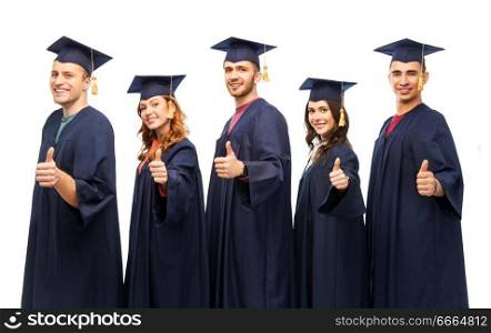 education, graduation and people concept - group of happy graduate students in mortar boards and bachelor gowns showing thumbs up over white background. graduate students showing thumbs up