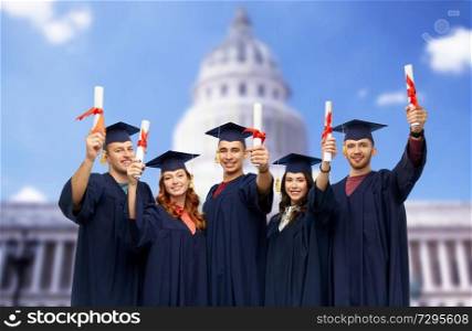education, graduation and people concept - group of happy graduate students in mortar boards and bachelor gowns with diplomas over white background. graduates in mortar boards with diplomas