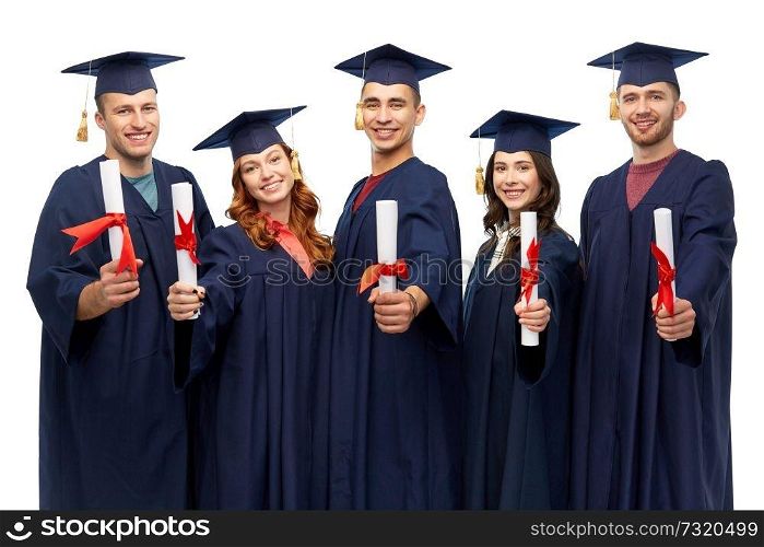 education, graduation and people concept - group of happy graduate students in mortar boards and bachelor gowns with diplomas over white background. graduates in mortar boards with diplomas
