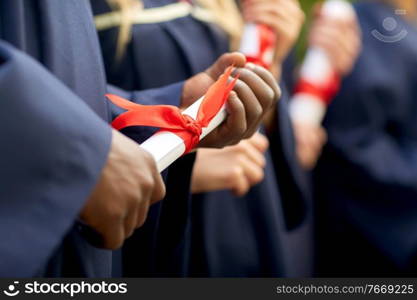 education, graduation and people concept - group of happy international graduate students in mortar boards and bachelor gowns with diplomas. graduate students in mortar boards with diplomas