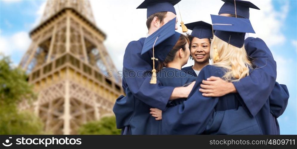 education, graduation and people concept - group of happy international students in mortar boards and bachelor gowns hugging over eiffel tower background